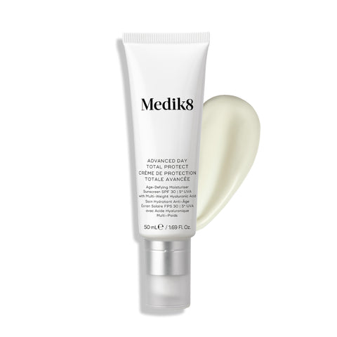 Tuba Medik8 Advanced Day Total Protect stojí na čistém bílém pozadí s velkým tahem krémově bílého hydratačního krému.