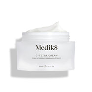 Otevřená dóza Medik8 C-Tetra Cream je zobrazena na čistém bílém pozadí s jemnými stíny.

Bílá matná skleněná dóza nese logo Medik8 a je označena jako C-TETRA CREAM Lipid Vitamin C Radiance Cream ve velikosti 50 ml. Na vrchu je viditelná bohatá vrstva bílé krémové textury, která zvýrazňuje její hydratační konzistenci.