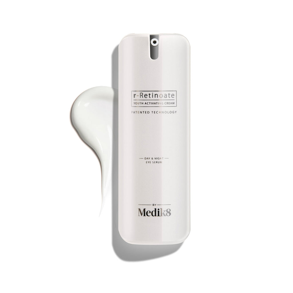 Bílá pumpičková lahvička r-Retinoate Day & Night Eye Serum s kapkou produktu vedle ní.