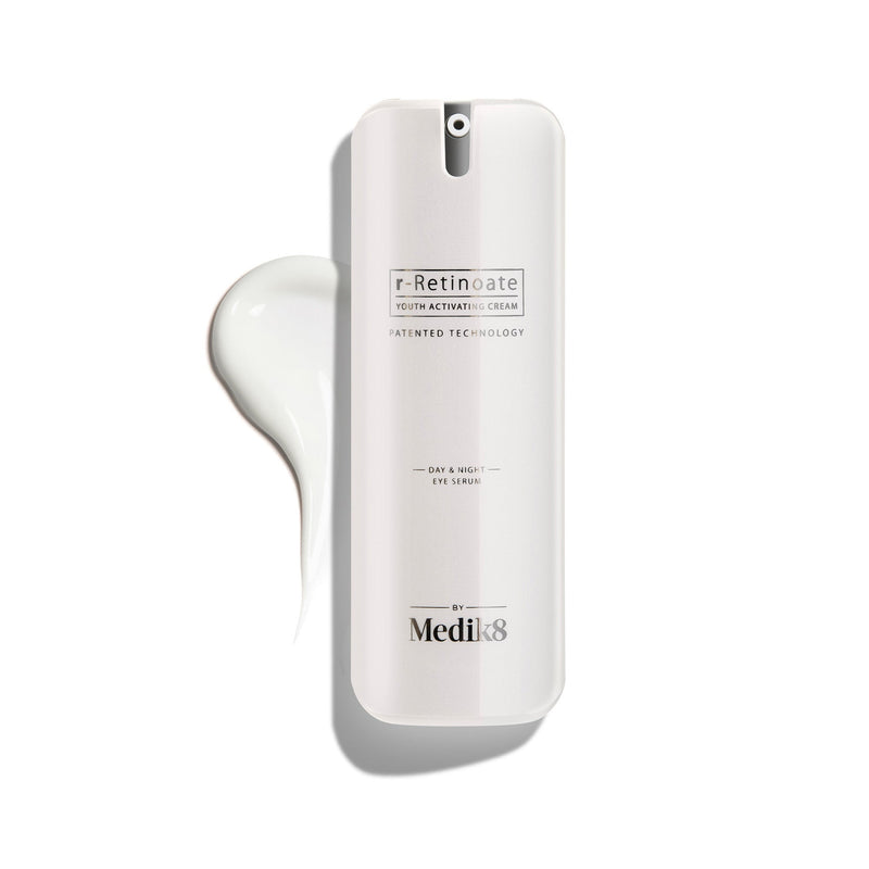 Bílá pumpičková lahvička r-Retinoate Day & Night Eye Serum s kapkou produktu vedle ní.