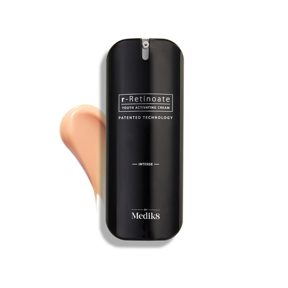 Lahvička Medik8 r-Retinoate Intense Youth Activating Cream je zobrazena na bílém pozadí spolu se vzorkem broskvově zbarvené krémové textury viditelným za ní.-40