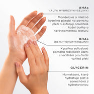 Detailní záběr rukou, které vytvářejí lehkou pěnu, s vyznačením hlavních složek přípravku Medik8 Surface Radiance Cleanse. Text popisuje AHA kyseliny (kyselinu mandlovou a mléčnou) pro povrchový peeling, BHA kyseliny (kyselinu salicylovou) k uvolnění ucpaných pórů a glycerin pro zvlhčení a hydrataci.