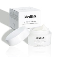 Dóza Medik8 C-Tetra Cream a její bílá kartonová krabička jsou zobrazeny na čistém bílém pozadí s jemnými stíny.

Otevřená bílá matná skleněná dóza nese logo Medik8 a je označena jako C-TETRA CREAM Lipid Vitamin C Radiance Cream ve velikosti 50 ml. Na povrchu je viditelná silná vrstva bílé krémové textury. Za dózou je bílá krabička s názvem produktu a částečným seznamem složek.