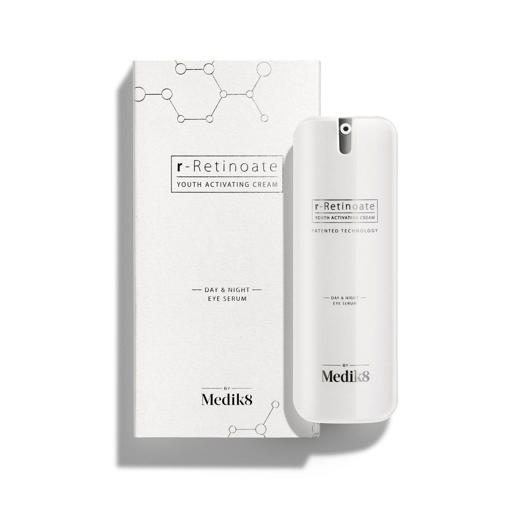 Bílá pumpičková lahvička r-Retinoate Day & Night Eye Serum stojí vedle své odpovídající bílé krabičky.