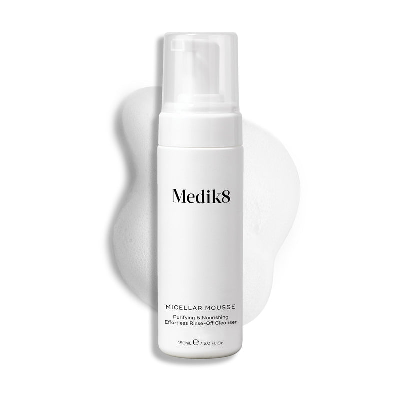 Pumpičková lahvička Medik8 Micellar Mousse zobrazená na bílém pozadí s rozmazanou stopou bílé pěny za ní, která zvýrazňuje texturu produktu.