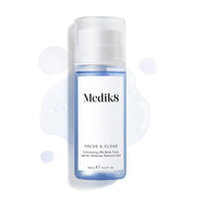 Láhev Medik8 Press & Clear (150 ml) na bílém pozadí, kolem ní jsou rozstříknuté kapky modrého tonika. Text zdůrazňuje složení  Exfoliating 2% BHA Tonic.