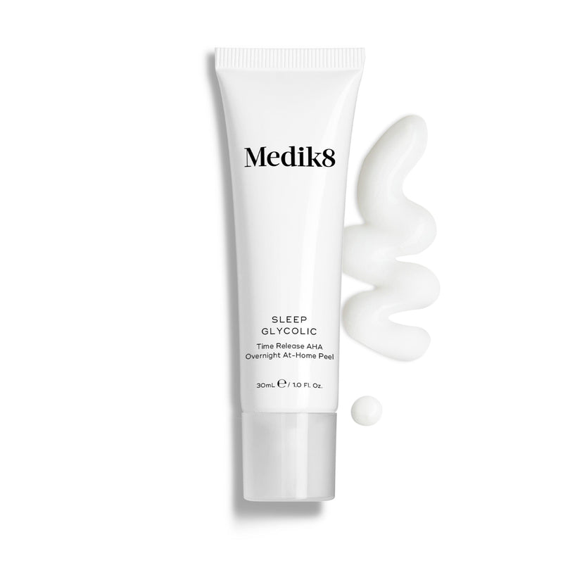 Lahvička Medik8 Sleep Glycolic stojí na čistém bílém pozadí spolu s vlnitým tahem a malou kapkou bílé krémové textury. Text uvádí, že produkt je 30ml noční at-home peeling s postupným uvolňováním AHA kyselin (Time Release AHA Overnight At-Home Peel).