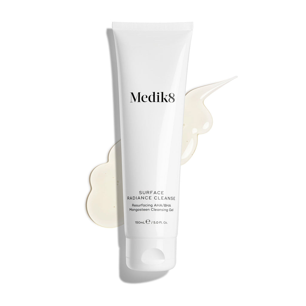 Tuba přípravku Medik8 Surface Radiance Cleanse je vyobrazena na čistém bílém pozadí s velkou skvrnou průsvitného gelu. Popisek uvádí, že se jedná o obnovující čisticí gel s AHA/BHA a mangostanem v balení o objemu 150 ml.