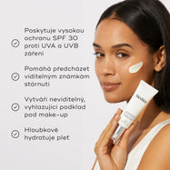 Usmívající se modelka s tahem bílého krému na tváři demonstruje aplikaci Advanced Day Ultimate Protect na teplém béžovém pozadí.