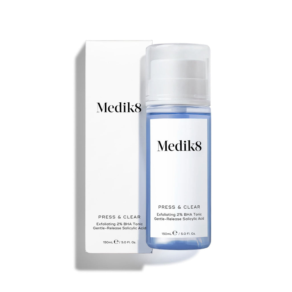 Láhev Medik8 Press & Clear s modrou tekutinou stojící vedle bílé krabičky. Podle popisu se jedná o  exfoliační tonikum s 2 % BHA  obsahující  salicylovou kyselinu s postupným uvolňováním. 