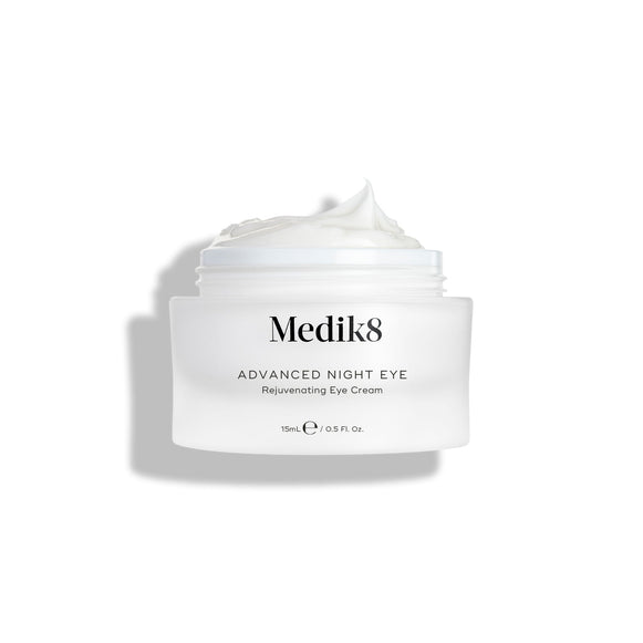 Kelímek krému Medik8 Advanced Night Eye stojí na bílém pozadí s odklopeným víčkem. Uvnitř je viditelný bohatý bílý krém, který zdůrazňuje jeho texturu.-26