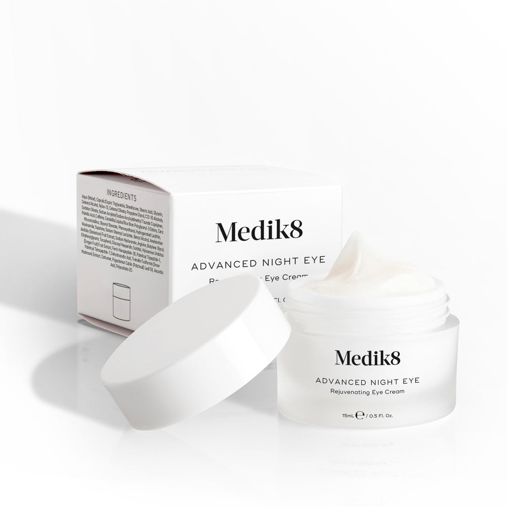 Otevřený kelímek krému Medik8 Advanced Night Eye stojí vedle své krabičky na bílém pozadí. Text zdůrazňuje složení „Rejuvenating Eye Cream“ (omlazující oční krém) a objem 15 ml.