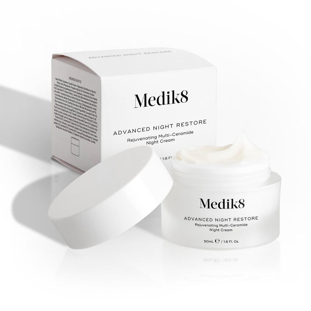 Otevřená dóza Medik8 Advanced Night Restore stojí s bílým víčkem opřeným vedle ní a s krabičkou produktu umístěnou v pozadí.

Obrázek zvýrazňuje bohatou texturu krému a čistý design obalu.