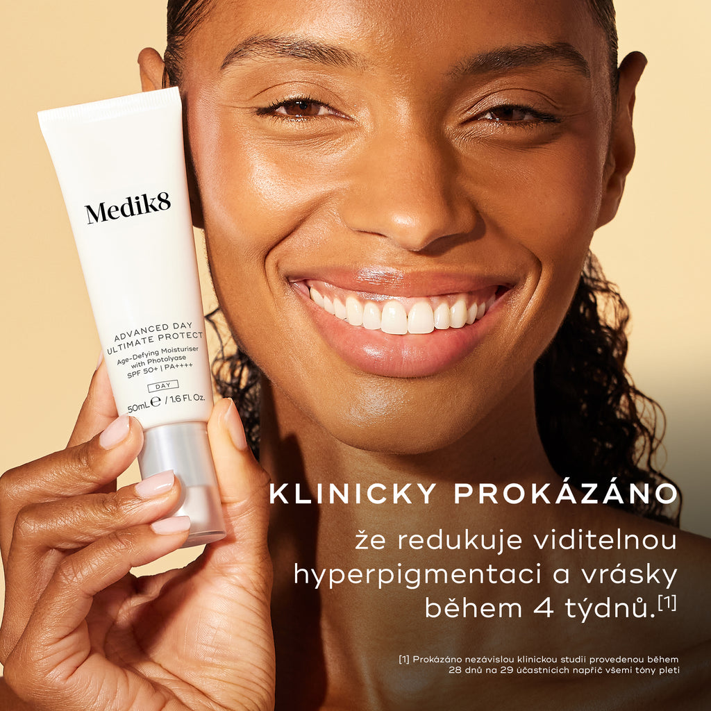 Detailní záběr usmívající se ženy se zářivou pletí, která drží tubu přípravku Advanced Day Ultimate Protect. Text uvádí: „KLINICKY PROKÁZÁNO, že za 4 týdny redukuje viditelnou hyperpigmentaci a vrásky.“