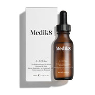 Jantarová skleněná lahvička séra Medik8 C-Tetra Lipid Vitamin C Radiance Serum je zobrazena vedle své bílé kartonové krabičky. Oba produkty jsou umístěny na čistém bílém pozadí s jemným stínem.