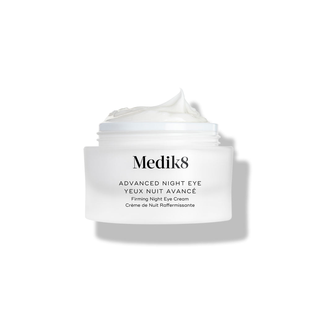 Kelímek krému Medik8 Advanced Night Eye stojí na bílém pozadí s odstraněným víčkem. Bohatý bílý krém je viditelný uvnitř kelímku a zdůrazňuje jeho texturu.