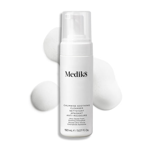 Lahvička čisticího přípravku Medik8 Calmwise Soothing Cleanser s pumpičkou je zobrazena na bílém pozadí s tahem bílé pěny za ní, který zdůrazňuje texturu produktu.