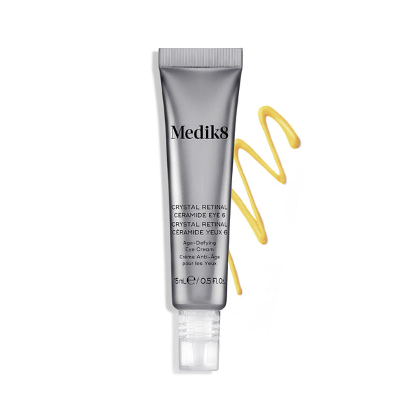 Tuba krému Medik8 Crystal Retinal Ceramide Eye 6 vedle klikatého tahu žlutého krému na bílém pozadí.-8