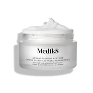 Otevřený kelímek krému Medik8 Advanced Night Restore s bohatou špičkou bílého krému na povrchu na čistém bílém pozadí, která zdůrazňuje jeho jemnou, obnovující texturu.