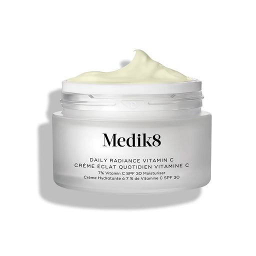 Skleněný kelímek krému Medik8 Daily Radiance Vitamin C je zobrazen otevřený s výraznou špičkou světle žlutého krému na povrchu. 