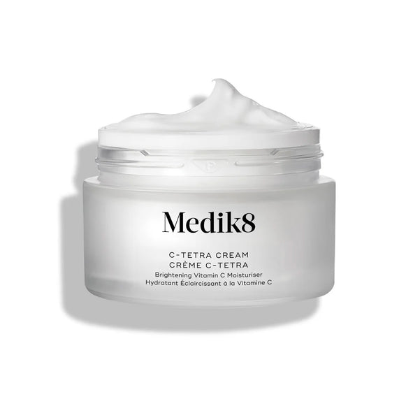 Otevřený kelímek krému Medik8 C-Tetra Cream je zobrazen na čistém bílém pozadí s jemnými stíny. Bílý matný skleněný kelímek nese logo Medik8 a označení „C-TETRA CREAM Lipid Vitamin C Radiance Cream“ o objemu 50 ml. Na povrchu kelímku je viditelná hustá spirála bílého krému, která zdůrazňuje jeho hydratační texturu.-9