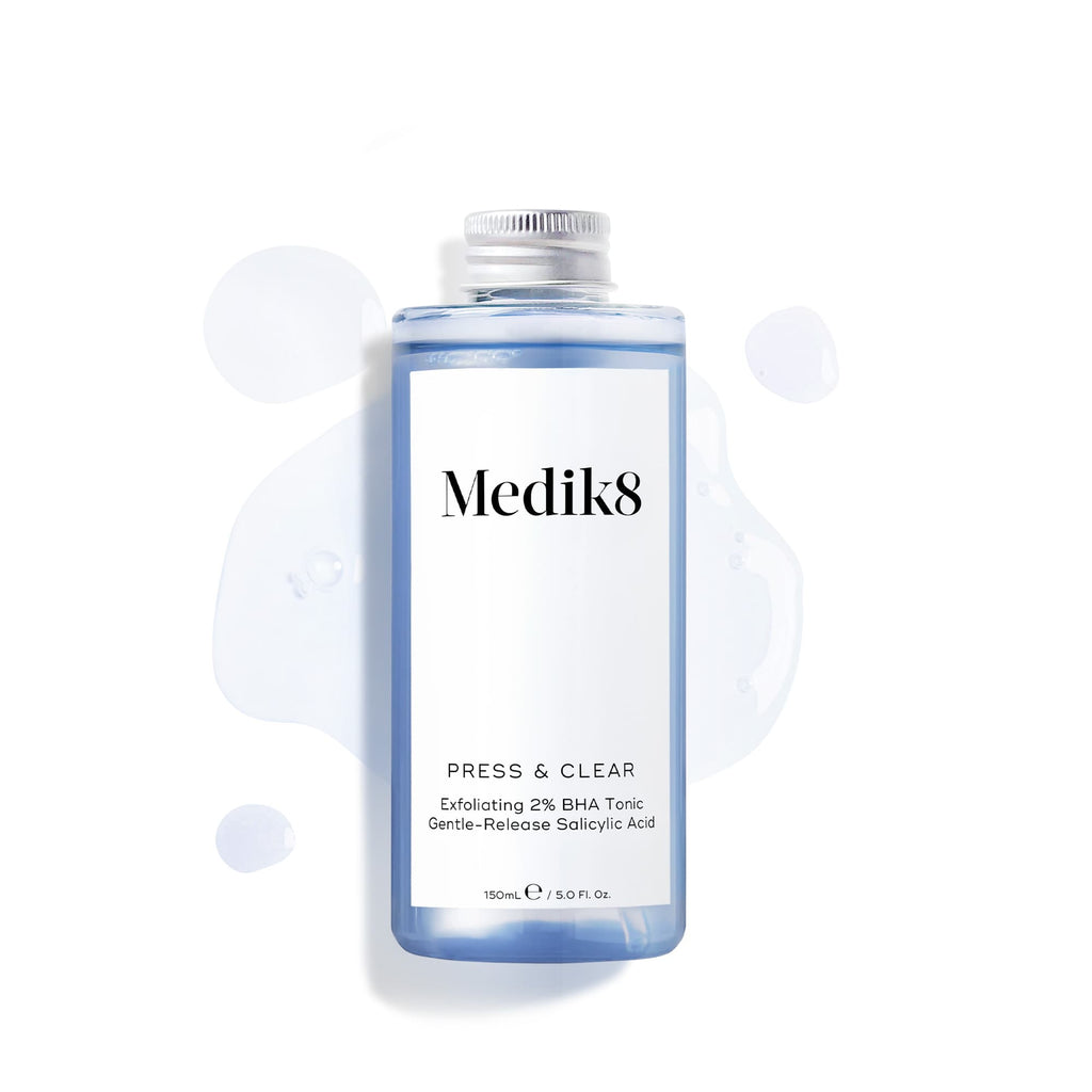 Náhradní lahvička (150 ml) tonika Medik8 Press & Clear se stříbrným šroubovacím uzávěrem, vyobrazená na bílém pozadí s modrými kapkami tekutiny. Text uvádí, že obsahuje kyselinu salicylovou s postupným uvolňováním. 